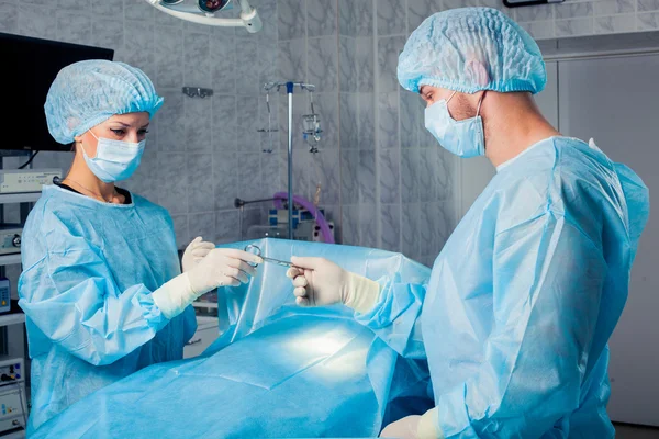 Equipo de cirujanos que trabaja con monitorización de pacientes en quirófano. Aumento de mamas . — Foto de Stock