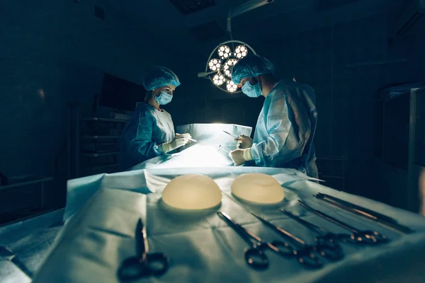 Equipo de cirujanos que trabaja con monitorización de pacientes en quirófano. Aumento de mamas . —  Fotos de Stock