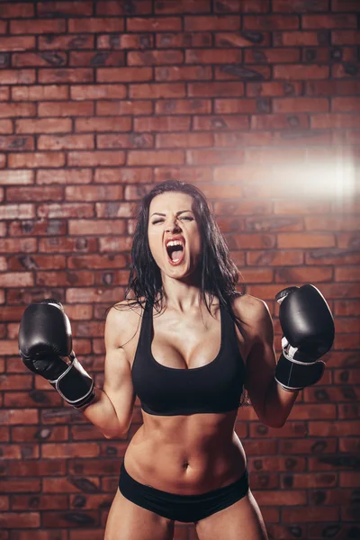 Junges sexy Mädchen mit Boxhandschuhen, auf der Hintergrundwand aus rotem Backstein. — Stockfoto