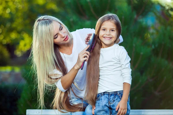 Mujer cepillando su hija pelo al aire libre jeans —  Fotos de Stock