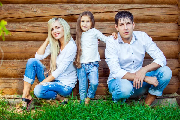 Mladá rodina se nachází v blízkosti dřevěného domu — Stock fotografie