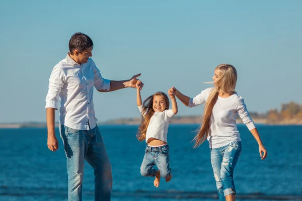 Familia feliz que juega en la playa. Concepto de familia amistosa —  Fotos de Stock