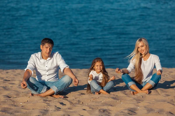 Familia en la playa. postura de loto. vaqueros . —  Fotos de Stock