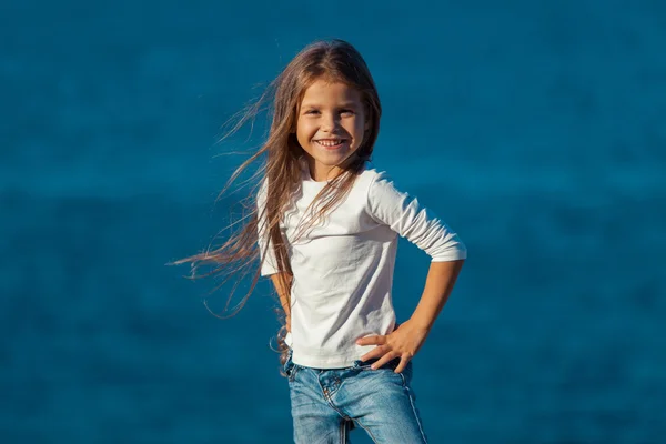 Entzückend glücklich lächelndes kleines Mädchen im Strandurlaub. Jeans. — Stockfoto