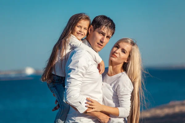 年轻的家庭，在拥抱水的背景上的蓝色牛仔裤 — 图库照片