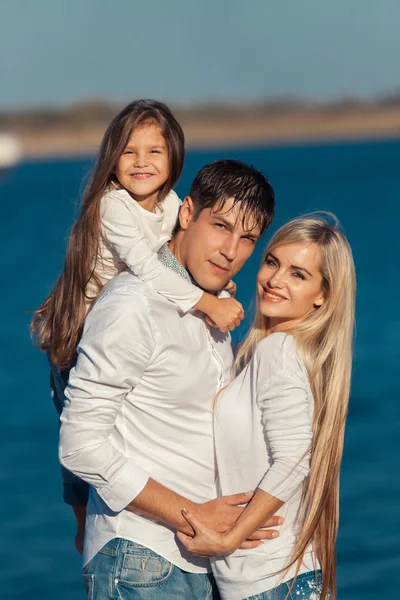 年轻的家庭，在拥抱水的背景上的蓝色牛仔裤 — 图库照片