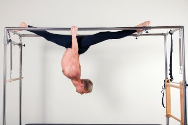 Pilates aerobic instructor man in cadillac fitness exercise acrobatic upside down balance