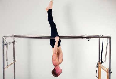 Pilates aerobic instructor man in cadillac fitness exercise acrobatic upside down balance