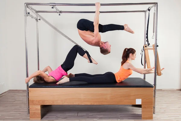 Pilates aerobic instructor a group of three people in cadillac fitness exercise