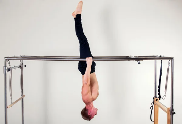 Pilates aerobic instructor man in cadillac fitness exercise acrobatic upside down balance — Zdjęcie stockowe