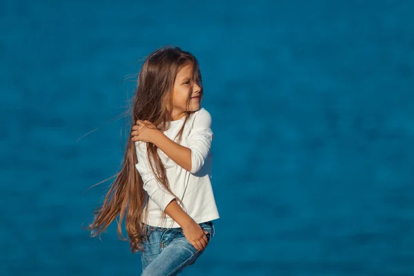 Entzückend glücklich lächelndes kleines Mädchen im Strandurlaub. Jeans. — Stockfoto