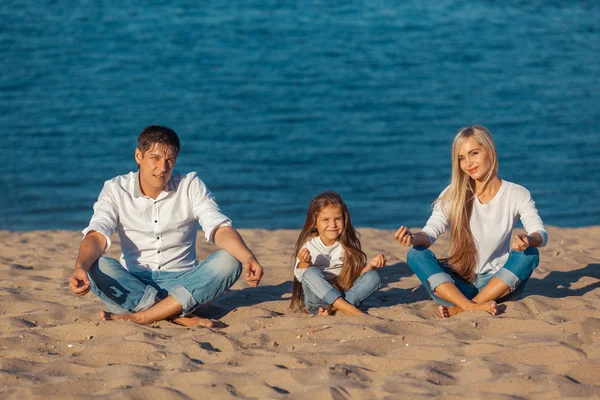 Famiglia in spiaggia. postura del loto. jeans . — Foto Stock