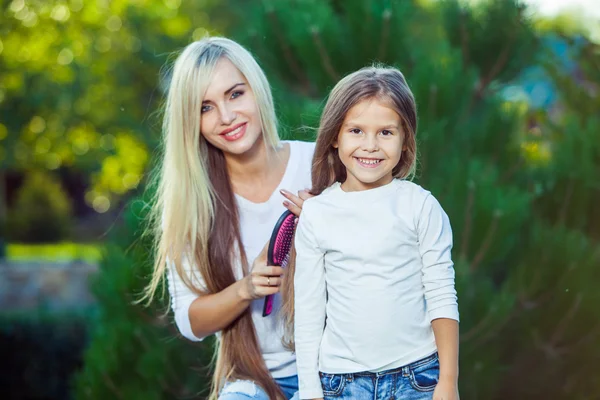 Mujer cepillando su hija pelo al aire libre jeans —  Fotos de Stock