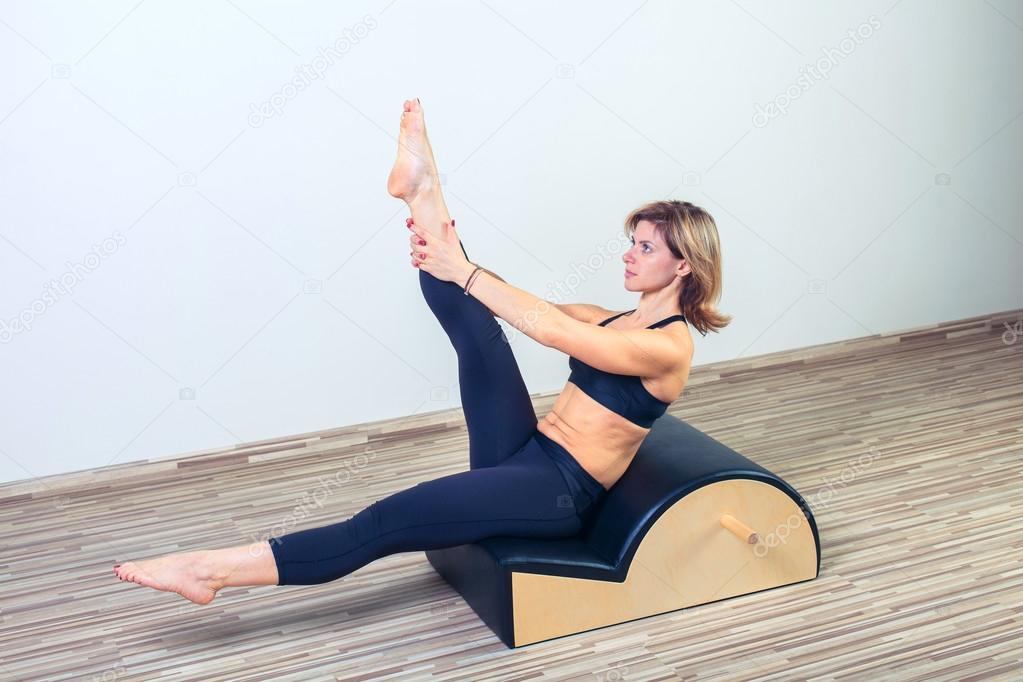 Pilates, fitness, sport, training and people concept -  woman doing  exercises on small barrel