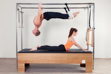 Pilates aerobic instructor woman and man in cadillac fitness exercise