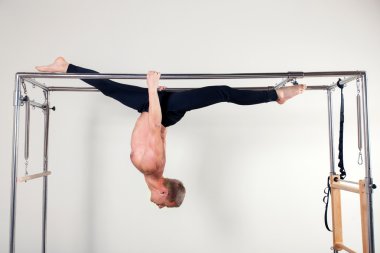 Pilates aerobic instructor man in cadillac fitness exercise acrobatic upside down balance