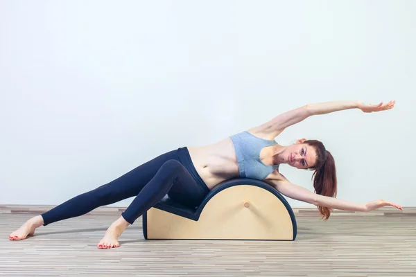 Pilates, fitness, deporte, entrenamiento y concepto de personas - mujer haciendo ejercicios en barril pequeño — Foto de Stock