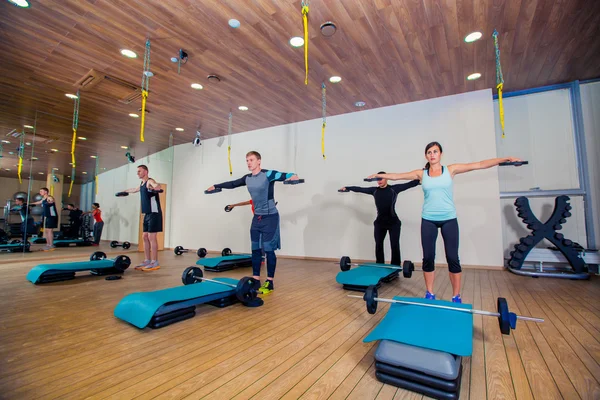 Concepto de deporte, fitness, estilo de vida y personas: músculos de flexión grupal con barras en el gimnasio —  Fotos de Stock