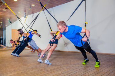 İnsanlar fitnes salonunda bir bant ile egzersiz yapmak. Trx
