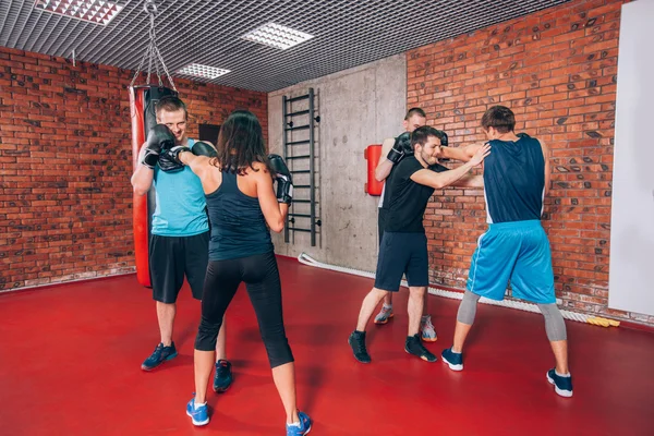 Boxing aerobox group with personal trainer man at fitness gym, gloves, punching bag