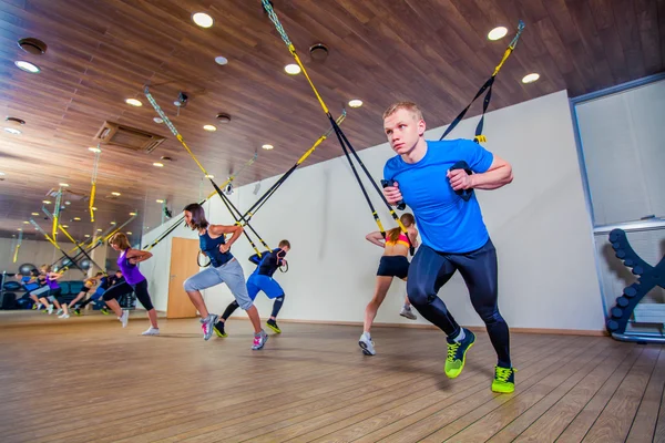 Lidé se fitness cvičení s kapelou v tělocvičně. TRX — Stock fotografie