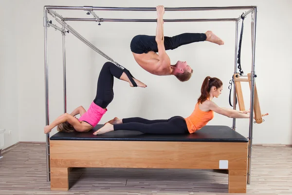 Pilates instructor aeróbico un grupo de tres personas en el ejercicio de la aptitud del cadillac — Foto de Stock