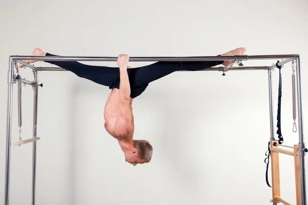 Pilates homem instrutor aeróbio em cadillac fitness exercício acrobático de cabeça para baixo equilíbrio — Fotografia de Stock