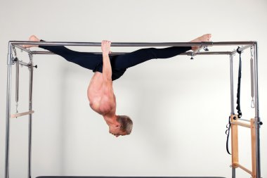 Pilates aerobic instructor man in cadillac fitness exercise acrobatic upside down balance