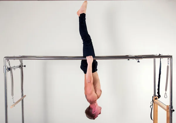 Pilates aérobie instructeur homme en exercice de remise en forme cadillac acrobatique à l'envers équilibre — Photo