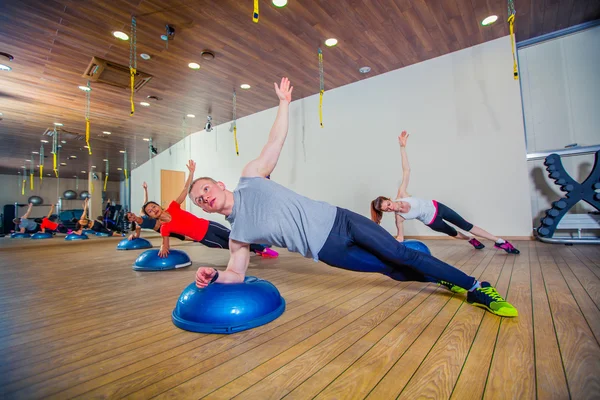 Pessoas no health club com personal trainer, aprendendo a forma correta. bosu — Fotografia de Stock