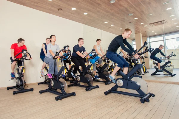 Ομάδα ανθρώπων γυμναστήριο σε μηχανήματα, Ποδηλασία στην τάξη — Φωτογραφία Αρχείου
