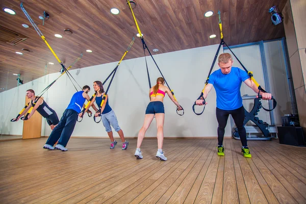 Människor gör Fitness Motion med ett band i gymmet. TRX — Stockfoto