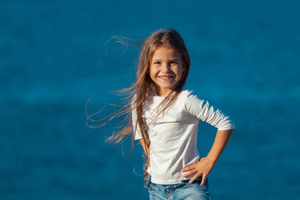 Entzückend glücklich lächelndes kleines Mädchen im Strandurlaub. Jeans. — Stockfoto