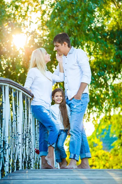 Máma, táta a dítě směje, objímání, užívat přírodu mimo. v modré džíny bílé košile — Stock fotografie