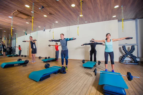 Esporte, fitness, estilo de vida e conceito de pessoas - músculos de flexão de grupo com sinos no ginásio — Fotografia de Stock