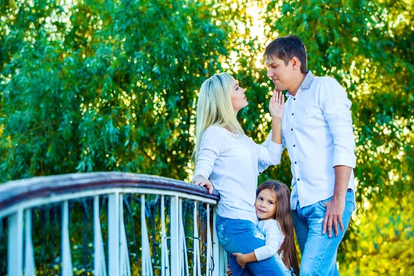 Mamãe, papai e criança rindo abraçando, curtindo a natureza lá fora. em azul jeans camisas brancas — Fotografia de Stock
