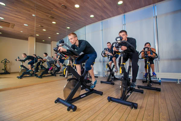 Ομάδα ανθρώπων γυμναστήριο σε μηχανήματα, Ποδηλασία στην τάξη — Φωτογραφία Αρχείου