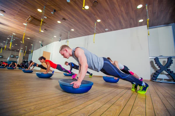 Persone al centro benessere con personal trainer, imparare la forma corretta. bosu — Foto Stock