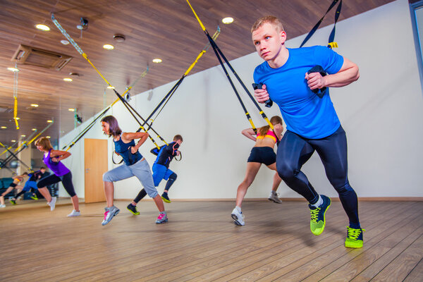 People make fitnes exercise with a band in the gym. TRX