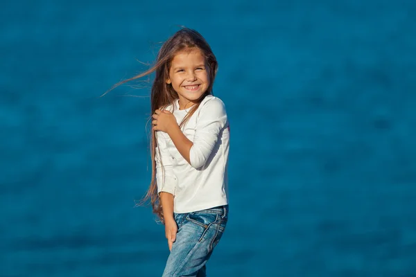 Entzückend glücklich lächelndes kleines Mädchen im Strandurlaub. Jeans. — Stockfoto