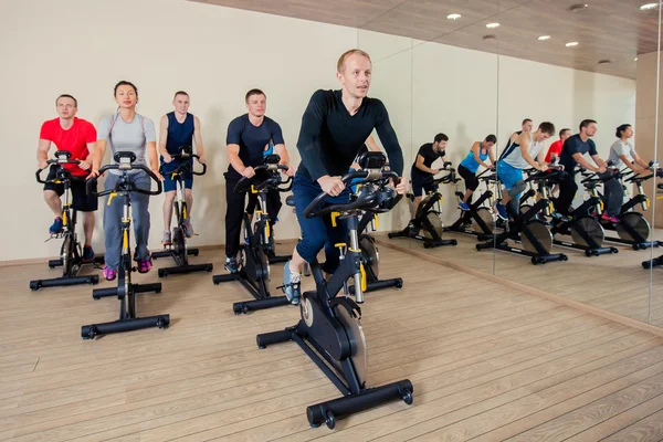 Grupp gym människor på maskiner, cykling i klass — Stockfoto