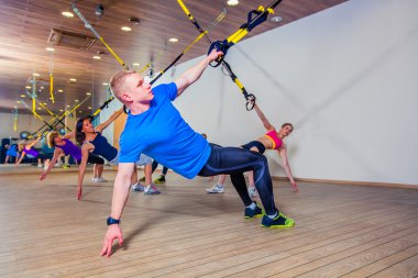 İnsanlar fitnes salonunda bir bant ile egzersiz yapmak. Trx