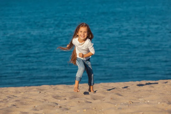 Adorabil fericit zâmbind fetiță în vacanță pe plajă. blugi . — Fotografie, imagine de stoc