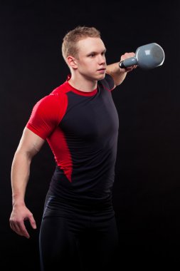Siyah arka plan üzerine kettlebellss ile ayakta bir adam portresi