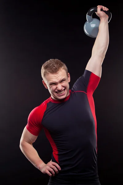 Retrato de un hombre de pie con kettlebellss sobre fondo negro — Foto de Stock