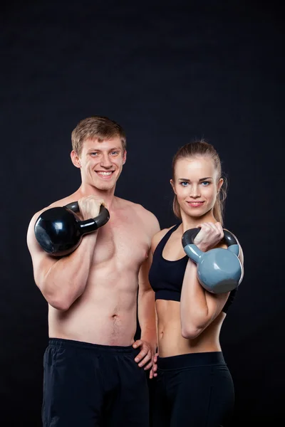 Aptidão atraente pessoas segurando kettlebells isolado sobre fundo cinza — Fotografia de Stock