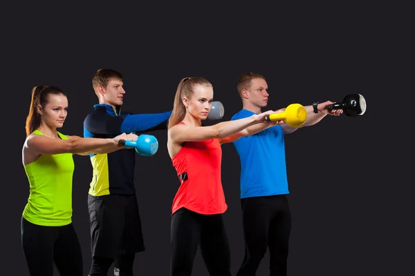 Gruppe sportlicher Menschen mit Kettlebells isoliert auf grauem Hintergrund — Stockfoto