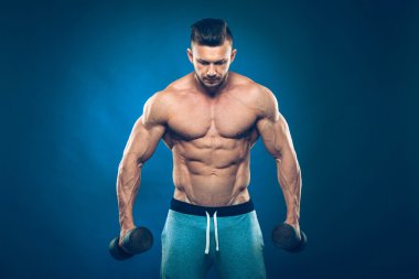 Dumbell ağırlık mı koyu arka plan üzerinde bir kas delikanlı closeup