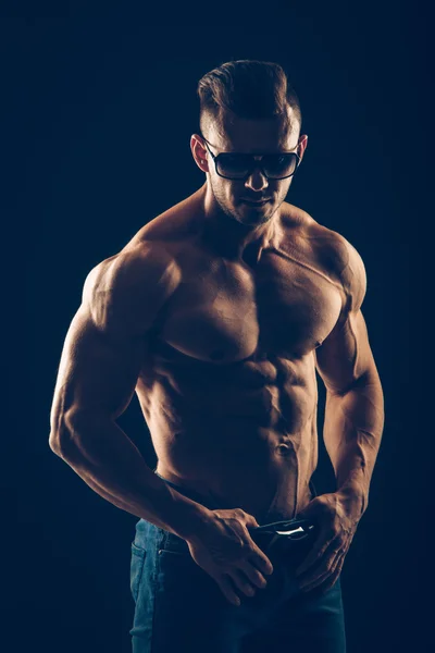 Sterke atletische man in zonnebril op zwarte achtergrond — Stockfoto
