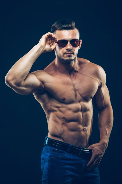 Сильний спортивний чоловік в сонцезахисних окулярах на чорному тлі — стокове фото
